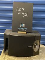Bose 201 Series V black bookshelf speaker with a note indicating lot number, showing left side with port and Bose logo.