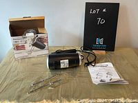 Brentwood black hand mixer with beaters, user guide, and original packaging on a beige cloth background.