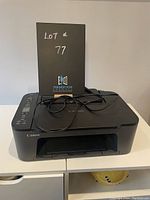 Canon Pixma TS3429 printer on a white surface with power cord placed on top, showing overall condition and design.