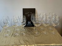 Photo of all 12 crystal wine glasses on table with a sign in background showing lot number