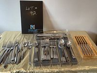 Wide shot showing all cutlery items arranged on a table with a black lot identification board.