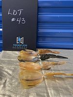 Photo of four hand carved Asian dragon handle serving spoons laid on silver cloth with a black sign mark.