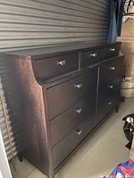 Full angled side view of the two-tiered chocolate brown dresser showing drawer layout and wear.