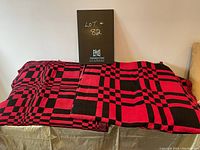 Two handwoven textiles laid side by side displaying their red and black geometric patterns.