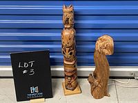Full view of both totem pole and driftwood sculpture side by side against blue background