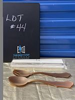 Salad serving spoon and fork in gold tone placed on a gold fabric surface, with original Sabre Paris box in background.