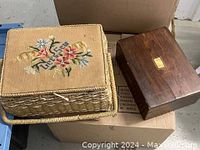 Two sewing boxes side by side; one woven with embroidered needlepoint lid, the other a dark wood box with small brass plate.