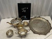 Silverplate teapot set with tray, creamer, and sugar bowls arranged together showing details and condition.