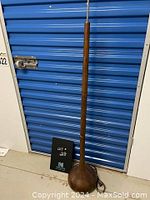 Full length photo of the teak floor lamp showing wooden base and part of metal stand, cord visible on the floor