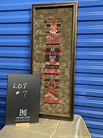 Full view of framed textile wall art showing three vertically arranged traditional Peruvian woven panels in frame.