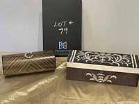 Two travel jewelry boxes presented side by side, one cylindrical with pearl decoration and the other rectangular with floral inlay.