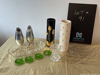 Full view of the lot including silver-colored bud vases, ceramic vases, green glass candle holders, and clear glass candy dish on table