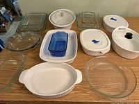 Overview of bakeware items on wooden table including varied dishes and lids