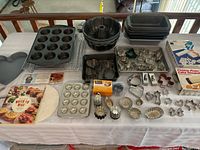 Baking lot showing pans, trays, cookie cutters, tins, baking liners and cooling rack arranged on table