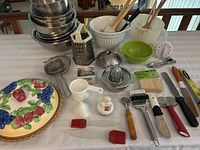 Full lot view showing covered pie plate, mixing bowls, grater, utensils, strainers, timer, and other kitchen tools.
