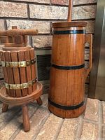 View of both wooden items together showing butter churn with handle and plunger and wine press with screw mechanism