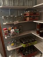 Shelves filled with empty and filled canning jars, some boxed lids and packaging supplies