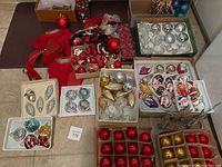Multiple boxes of assorted ornaments and red fabric bows laid out on table