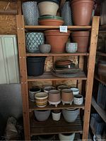 Full view of wooden shelving unit with six shelves holding various gardening pots of different materials and sizes.