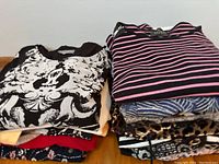 Stack of folded blouses showing variety in patterns and colors including floral, stripes, and animal print