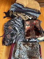 Top view of the folded scarves showing multiple patterns and colors including beige, black, brown, and animal print