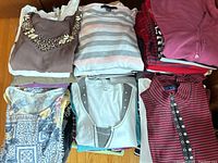 Overview of multiple folded ladies' short-sleeve tops including brown embellished, striped, and solid colors