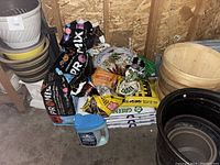 Photo showing several stacked garden pots including beige and white ribbed resin pot, and bags of garden soil and soil mix.