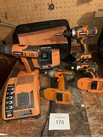 Complete set on workbench showing drills, impact driver, batteries, chargers and bag