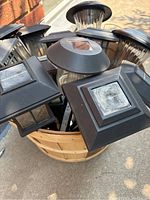 Top-down view showing multiple solar garden lights with various top styles clustered in wooden bushel basket.