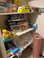 Shelves with various boxes of food wraps, plastic films, foil, and bags, mostly opened.
