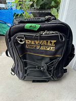 Front view of DEWALT ToughSystem 2.0 black tool bag with yellow logo, bungee cord, and dual zipper pockets visible.