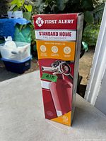 Photo of First Alert Standard Home Fire Extinguisher in original packaging showing front of box with product features and branding.