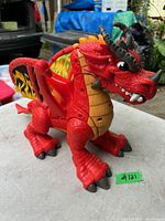 Red Fisher Price toy dragon on table with visible orange accents, wings with flame design, and black horns.