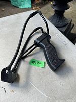 Top angled frontal view of black handheld slingshot showing textured grip and elastic bands attached to pouch.