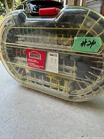Photo of closed rotary tool accessory set case showing brand label and quantity (300 pieces) inside translucent plastic case with red latch.