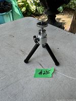 Mini camera tripod with black and chrome telescoping legs shown folded