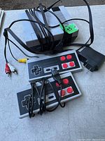 Nintendo Mini Anniversary Edition console with two wired controllers, AV cables, and power adapter visible on a surface