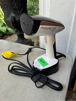 Image showing Rowenta handheld garment steamer angled to show steam head, power cord, and overall clean condition with no visible damage.
