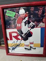Signed photo of Eric Lindros in Philadelphia Flyers hockey uniform, framed in red with autograph visible.