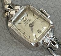 Close-up of watch face showing rectangular dial, Gruen Precision logo, Arabic 12 and 6, decorative lugs with clear stones