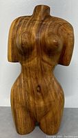 Front side of the wooden carved nude female torso statue showing detailed carving and wood grain.