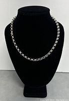 Necklace displayed on black bust showing full length and style.
