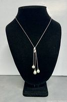 Front view of silver necklace displayed on black bust, showing the three pearls suspended at the chain's end.