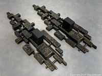 Pair of Brutalist wall sconce candleholders shown from above on a flat surface, highlighting geometric relief and weathered finish.