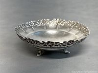 Side view showing footed base and floral scalloped edge on silver bowl