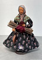 Front view of the vintage terracotta dressed santon holding twigs and a bucket, showing base signature and detailed clothing.