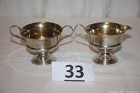 Photo of the pair of matching sterling silver sugar and creamer showing overall shape, handles, and pedestal bases.