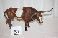 Front and side view showing the brown and white color pattern, realistic sculpting, and 14.5 inch length of the bull model.
