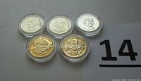 Five gold-plated presidential $1 coins arranged in a cluster with plastic protective cases clearly visible, showing detailed presidential portraits.