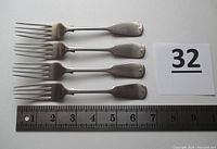 Four sterling silver fiddle forks laid next to a ruler showing length of 6.5 inches each.